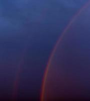 duplo arco-íris embaçado em um céu escuro e nublado foto