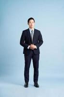 retrato de empresário asiático vestindo terno sobre fundo azul foto