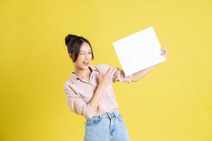 imagem do uma bonita ásia menina segurando uma branco Painel publicitário foto