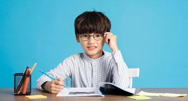 retrato do escola Garoto sentado e estudando em uma azul fundo foto