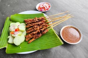 frango satay ou frango satay servido com lontong, arroz bolo e amendoim molho. servido em banana sair foto