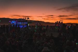 pessoas caminhando para pôr do sol às uma festival dentro a deserto às a queimando homem festival. foto