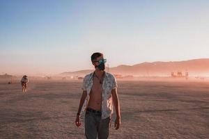 pessoas caminhando para pôr do sol às uma festival dentro a deserto às a queimando homem festival. foto