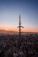 pessoas caminhando para pôr do sol às uma festival dentro a deserto às a queimando homem festival. foto