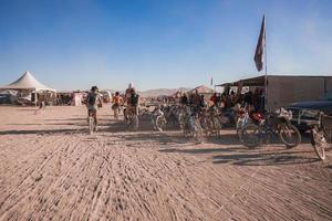 pessoas caminhando para pôr do sol às uma festival dentro a deserto às a queimando homem festival. foto