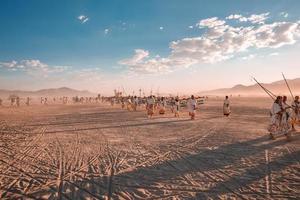 pessoas caminhando para pôr do sol às uma festival dentro a deserto às a queimando homem festival. foto