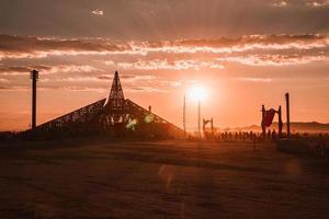 pessoas caminhando para pôr do sol às uma festival dentro a deserto às a queimando homem festival. foto