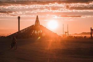 pessoas caminhando para pôr do sol às uma festival dentro a deserto às a queimando homem festival. foto