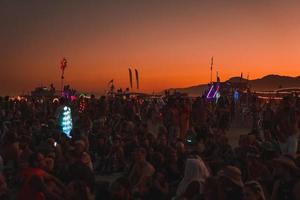 pessoas caminhando para pôr do sol às uma festival dentro a deserto às a queimando homem festival. foto