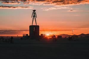 pessoas caminhando para pôr do sol às uma festival dentro a deserto às a queimando homem festival. foto