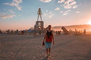 pessoas caminhando para pôr do sol às uma festival dentro a deserto às a queimando homem festival. foto