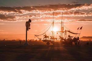 pessoas caminhando para pôr do sol às uma festival dentro a deserto às a queimando homem festival. foto