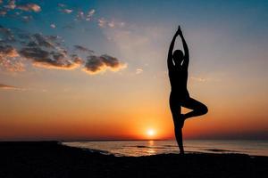 garota na praia fazendo ioga asana foto