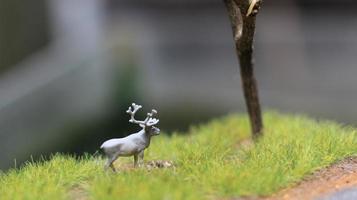 miniatura figura do uma alce comendo. uma Prado e árvore diorama. conceito do natureza e animais. foto