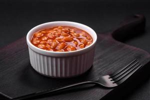 delicioso enlatado feijões dentro uma tomate dentro uma branco cerâmico tigela foto