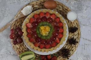 grande fruta torta com coberturas do morangos, uvas, kiwi e abacaxi. saboroso, doce e fresco. Comida conceito foto. foto