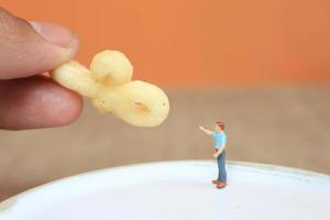 miniatura figura do uma criança interagindo com humano mãos dando Comida. foto