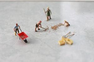 miniatura figuras do trabalhadores trabalhando juntos para mover grão. foto