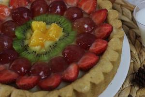 grande fruta torta com coberturas do morangos, uvas, kiwi e abacaxi. saboroso, doce e fresco. Comida conceito foto. foto