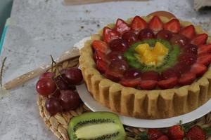 grande fruta torta com coberturas do morangos, uvas, kiwi e abacaxi. saboroso, doce e fresco. Comida conceito foto. foto