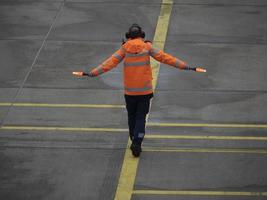 a operador ajudando pilotos do avião enquanto estacionamento às a terminal foto