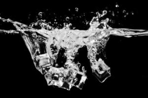 cubos de gelo na água com bolhas no fundo preto foto
