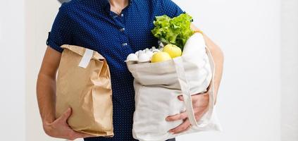 homem segurando cheio saco do diferente saudável Comida em uma de madeira mesa dentro a casa cozinha fechar acima foto