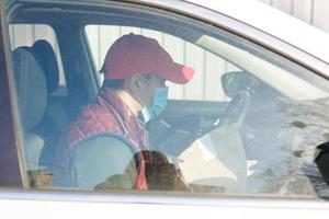 Entrega de carro. homem dentro protetora mascarar e médico luvas segurando uma papel caixa. Entrega serviço debaixo quarentena, doença surto, coronavírus covid-19 pandemia condições. foto