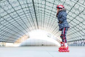 pequeno menina patins em rolo rinque foto