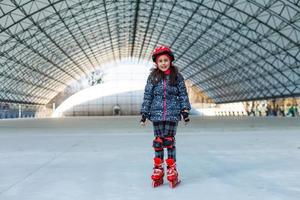 pequeno menina patins em rolo rinque foto