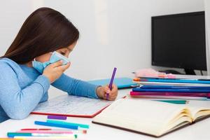 digital tecnologia Educação conceito. pequeno menina dentro uma protetora mascarar às distância casa escolaridade, quarentena foto