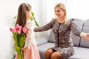 retrato do pequeno menina amoroso mãe segurando dela e tulipas foto