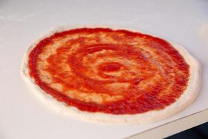 preparando pizza com marinara foto