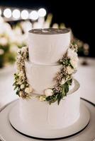 bolo branco de casamento em um alto suporte perto do pódio branco
