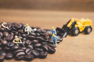 pessoas em miniatura trabalhando em grãos de café torrados foto