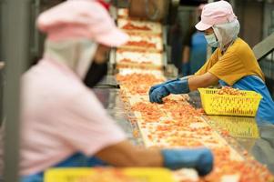 trabalhadores cortar tomates para enlatado tomate molho dentro industrial Produção padrões, industrial Produção do tomates e tomate colar, Comida indústria, Comida fábrica foto