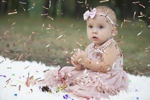 uma engraçado pequeno menina dentro uma brilhante confete. criança comemora 1 ano. lindo bebê. foto