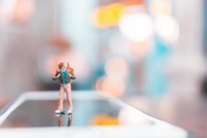 turista mochileiro em miniatura em um smartphone, conceito de viagens foto