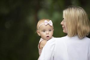 uma feliz mulher carrega uma um ano de idade filha dentro dela braços. foto