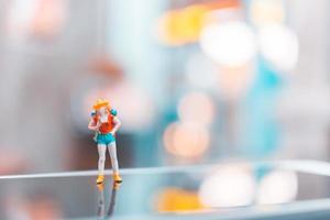 turista mochileiro em miniatura em um smartphone, conceito de viagens foto