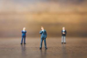 Empresários em miniatura em pé sobre um fundo de madeira foto