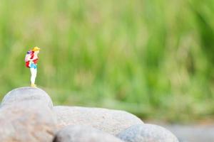 viajante em miniatura com uma mochila em pé e caminhando em um prado foto