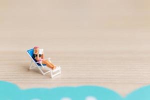 pessoas em miniatura tomando banho de sol na praia, conceito de verão foto