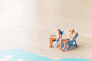 pessoas em miniatura tomando banho de sol na praia, conceito de verão foto