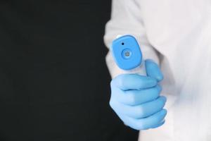 mão segurando termômetro infravermelho para medir a temperatura foto