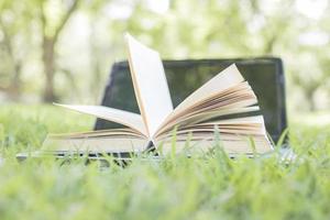 livro abrindo com laptop na grama verde como conceito de liberdade de conhecimento foto