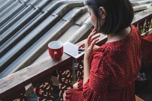 mulher sentada com um café e telefone em um terraço foto