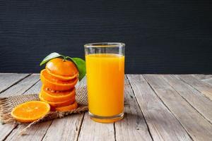 laranja fresca e suco de laranja em uma mesa de madeira foto