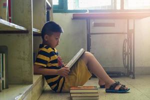 menino lendo um livro em uma biblioteca foto