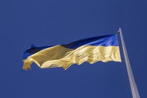 acenou ucraniano bandeira em mastro de bandeira contra azul céu foto